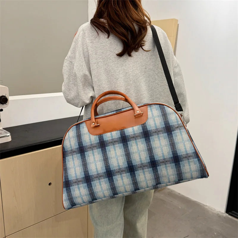 Blue plaid duffle bag with brown leather handles for travel