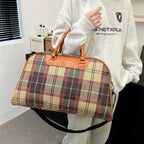 Plaid duffle bag with brown leather handles for travel