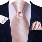 Navy suit with a pink tie, pocket square, and cufflinks on a white background